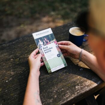 Hände halten die Radwanderkarte Brandenburg an der Havel, Blick auf das Coverbild mit Radfahrern.